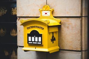 yellow postbriefkasten floating mailbox on brown concrete wall